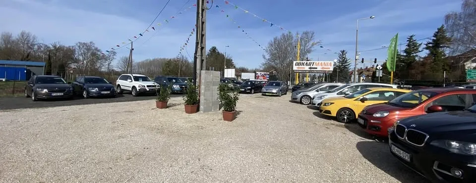 A Kartel Autó győri telephelye: kavicsos udvar sorba állított autókkal.